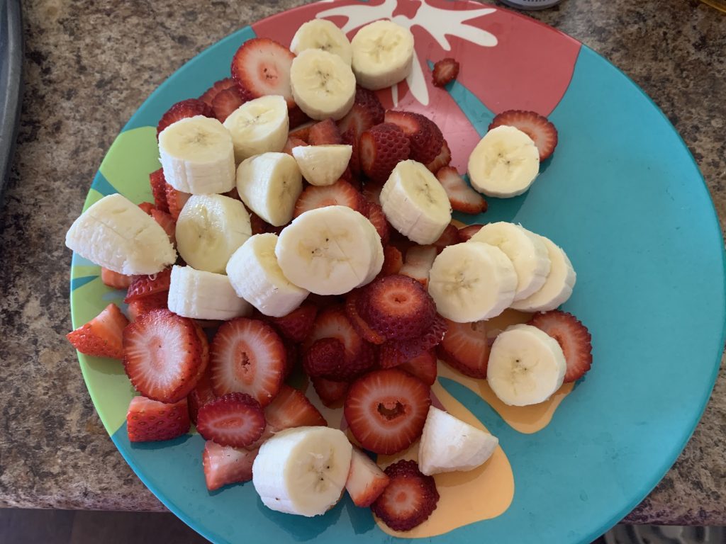 blue plate of cut up bananas and strawberries