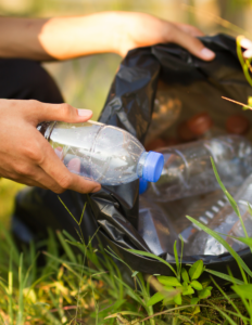 hand filling garbage bag with empty water bottle